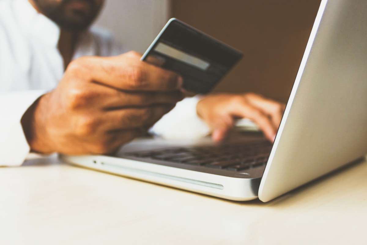 Pessoa usando laptop e cartão, simbolizando compras online e fraude no varejo